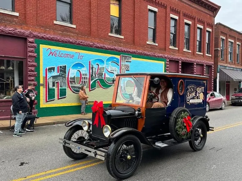 The Shine Brite Model T driving past the Welcome to Horse Cave mural during a hometown parade