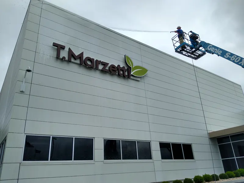 Lift crew washing a manufacturing plant wall