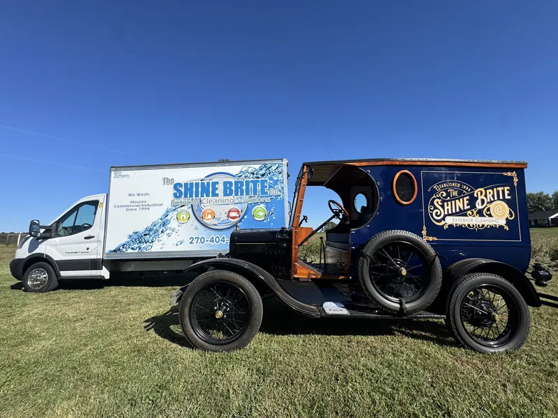 Restored Model T and modern Transit box truck, both in Shine Brite colors, parked on the grass